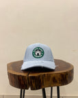 Gray cap with a green logo on a wooden block against a beige wall